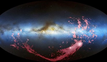 In this composite image, the Magellanic Stream is shown in pink. The Milky Way is the light blue band in the center of the image. The Magellanic Clouds, satellite galaxies of the Milky Way, are the white regions at the bottom right (David L. Nidever et al. / NRAO / AUI / NSF / Mellinger / Leiden / Argentine / Bonn Survey / Parkes Observatory / Westerbork Observatory / Arecibo Observatory)