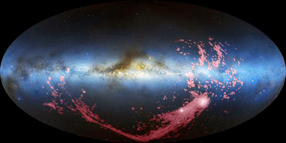 In this composite image, the Magellanic Stream is shown in pink. The Milky Way is the light blue band in the center of the image. The Magellanic Clouds, satellite galaxies of the Milky Way, are the white regions at the bottom right (David L. Nidever et al. / NRAO / AUI / NSF / Mellinger / Leiden / Argentine / Bonn Survey / Parkes Observatory / Westerbork Observatory / Arecibo Observatory)