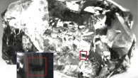 Top: monochrome image of USD 20 diamond taken under incident light, with the ringwoodite inclusion highlighted by a red square. Bottom: enlarged view of the area of the host diamond containing the ringwoodite inclusion; the shadow behind the rectangular area outlining the inclusion is probably a stress fracture in the diamond. Image credit: D.G. Pearson et al.