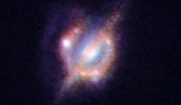 H-ATLAS J142935.3-002836, an object seen by the Hubble Space Telescope and the Keck-II telescope on Hawaii with the help of a gravitational lens. In this image one can see the foreground galaxy that is doing the lensing, which resembles how our Milky Way Galaxy would appear if seen edge-on; but around this galaxy there is an almost complete ring - the smeared out image of a star-forming galaxy merger far beyond. Image credit: ESO / NASA / ESA / W. M. Keck Observatory.