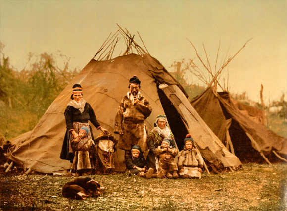 A Sami indigenous northern European family in Norway around 1900. The picture was probably taken in 1896 around the Kanstadfjord near Lødingen, Nordland. The adults on the left are Ingrid (born Sarri) and her husband Nils Andersen Inga. In front of the parents are Berit and Ole Nilsen. The lady on the right is Ellen, sister of Ingrid. In front of Ellen are the children Inger Anna and Tomas. The children of Inger Anna are reindeer herders still today. Detroit Publishing Co. print no. 7123.