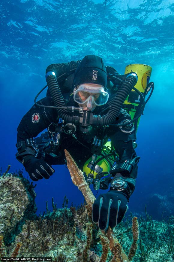 Return to Antikythera project chief diver Philip Short inspects the bronze spear recovered from the Antikythera Shipwreck. Image credit: Brett Seymour / Return to Antikythera.