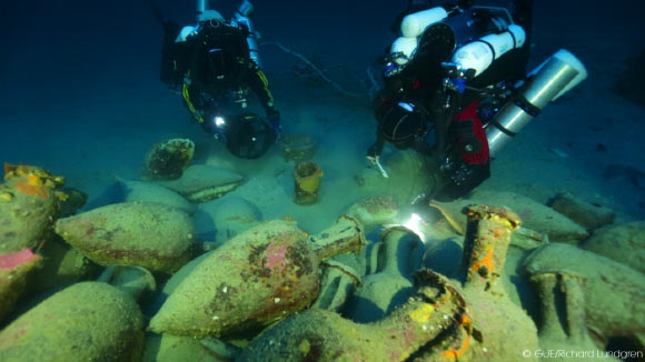 Divers illuminate artifacts of the Panarea III ship. Image credit: © Global Underwater Explorers.