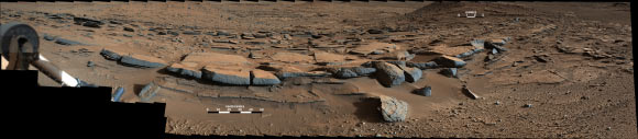 This view from the Mastcam on Curiosity looks southward at the Kimberley waypoint. In the foreground, multiple sandstone beds show systematic inclination to the south suggesting progressive build-out of the sediments toward Mount Sharp. At this location, about 1.6 km north of the base of Mount Sharp, these inclined beds can be traced up to about 100 meters in the direction of build-out. These inclined beds are interpreted as small deltas building out into a shallow lake. As sediment-laden river water encountered a standing body of water, the river current was forced to abruptly decelerate, leading to rapid deposition of sediment at the river mouth. This deposition led to formation of a delta. Continued supply of sediment by rivers flowing from the crater rim led to deltas building out into the lake towards the south. The camera recorded the component frames of this mosaic on March 25, 2014, during the 580th Martian day, or sol, of Curiosity's work on Mars. The color has been approximately white-balanced to resemble how the scene would appear under daytime lighting conditions on Earth. Image credit: NASA / JPL-Caltech / MSSS.