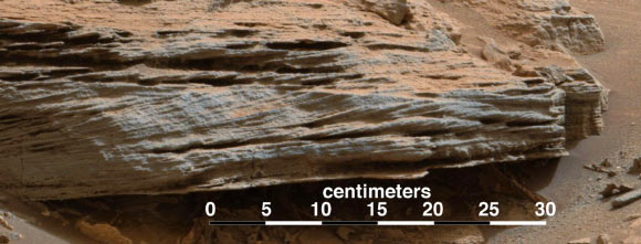 Cross-bedding seen in the layers of this Martian rock is evidence of movement of water recorded by waves or ripples of loose sediment the water passed over. This image was acquired by Curiosity at a target called Whale Rock in the basal geological unit of Mount Sharp. The camera took it during the 796th Martian day, or sol, of Curiosity's work on Mars - November 2, 2014. The color has been approximately white-balanced to resemble how the scene would appear under daytime lighting conditions on Earth. This example of cross-bedding shows evidence of small climbing ripples that migrate on top of each other - just above 10 in scale bar. This suggests currents of water entered into a lake basin, possibly flowing down the front of a delta, and then spread out across the lake floor, slowing down, and depositing sediment. Image credit: NASA / JPL-Caltech / MSSS.