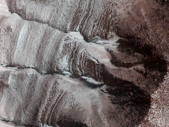 The frosted gullies in this image, captured by the HiRISE camera on November 13, 2014, are located along an irregularly shaped pit (about 15 km wide) within the impact crater in Sisyphi Planum. Image credit: NASA / JPL-Caltech / University of Arizona.