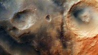 The Nili Fossae system, part of which is shown in this image, is an area of great geological interest near the giant Isidis impact basin, northeast of the Syrtis Major volcanic province. The system contains numerous troughs, one of which can be seen crossing the lower left of this image. On the plateau above, several depressions can be seen, some of them extending into the trough. A large, 55 km-diameter impact crater with a central pit can be seen on the right. This image was acquired by the High Resolution Stereo Camera on the Mars Express on 16 October 2014. North is to the right, east is up. Image credit: ESA / DLR / FU Berlin / CC BY-SA 3.0 IGO.