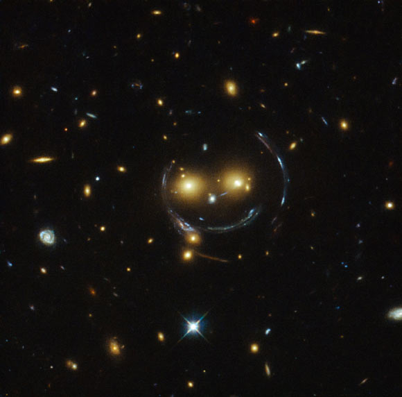 This image from Hubble shows the galaxy cluster SDSS J1038+4849 that appears to have two eyes and a nose as part of a happy face. Image credit: NASA / ESA / Judy Schmidt, geckzilla.org.