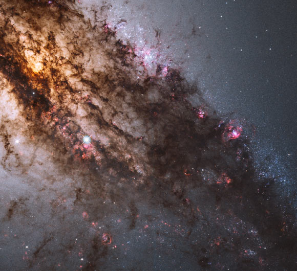 Resembling looming rain clouds on a stormy day, dark lanes of dust crisscross the giant elliptical galaxy NGC 5128, also known as Centaurus A. The warped shape of NGC 5128’s disk of gas and dust is evidence for a past collision and merger with another galaxy. The resulting shockwaves cause hydrogen gas clouds to compress, triggering a firestorm of new star formation. At a distance of just over 11 million light-years, NGC 5128 contains the closest active galactic nucleus to Earth. The center is home for a supermassive black hole that ejects jets of high-speed gas into space, but neither the supermassive black hole or the jets are visible in this image. Image credit: NASA / ESA / Hubble Heritage / STScI / AURA / Hubble Collaboration / R. O'Connell, University of Virginia / WFC3 Scientific Oversight Committee.