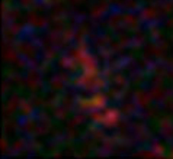 The extremely distant galaxy A1689-zD1 appears on this picture as the elongated reddish object; its light has been magnified by a factor of more than 9 by the massive gravitational lensing effect of the galaxy cluster Abell 1689. Image credit: J. Richard / ESO.