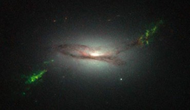 This Hubble image shows ghostly green filaments, lying within galaxy 2MASX J22014163+1151237. This filament was illuminated by a blast of radiation from a quasar - a very luminous and compact region that surrounds the supermassive black hole at the center of its host galaxy. Its bright green hue is a result of ionized oxygen, which glows brightly at green wavelengths. Image credit: NASA / ESA / W. Keel, University of Alabama.