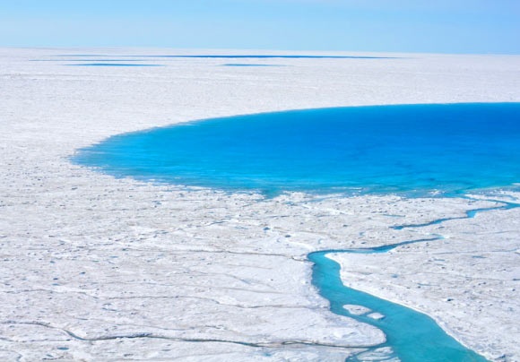 Thousands of supraglacial lakes form each spring and summer on top of the Greenland Ice Sheet. When they drain, they send torrents of water to the base of the ice sheet, lubricating the interface between rock and ice. That allows the ice sheet to flow faster to the ocean and discharge ice into ocean, which causes sea levels to rise faster. Image credit: Laura Stevens / Woods Hole Oceanographic Institution.