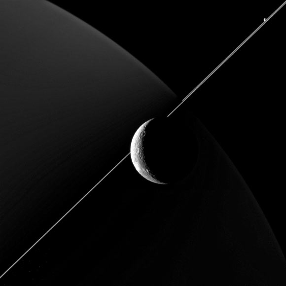 This image of Dione was taken with the wide-angle camera aboard Cassini on June 16, 2015. Also making an appearance in this image is Saturn’s moon Enceladus, seen in the upper right, just above the bright line of Saturn’s rings. Image credit: NASA / JPL-Caltech / Space Science Institute.