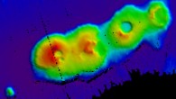 A 3D relief map of the volcanic cluster on the sea floor. The sea floor is represented by a dark blue color and there are four calderas rising out of the sea floor in shades of green, yellow, orange and red. Image credit: University of New South Wales.