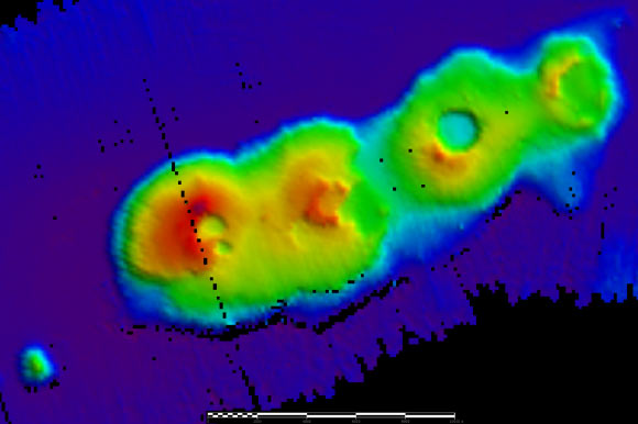A 3D relief map of the volcanic cluster on the sea floor. The sea floor is represented by a dark blue color and there are four calderas rising out of the sea floor in shades of green, yellow, orange and red. Image credit: University of New South Wales.