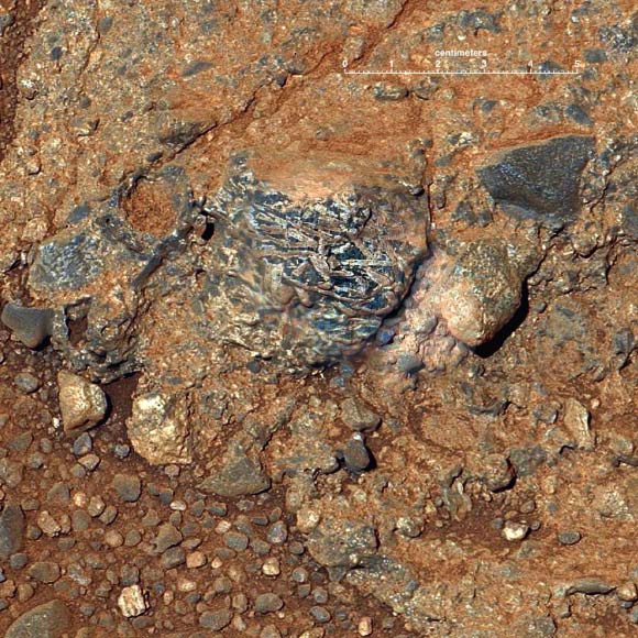 Igneous clast named Harrison embedded in a conglomerate rock in Gale crater shows elongated light-toned feldspar crystals. The mosaic merges an image from Curiosity’s Mastcam with higher-resolution images from ChemCam’s Remote Micro-Imager. Image credit: NASA / JPL-Caltech / LANL / IRAP / U. Nantes / IAS / MSSS.