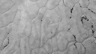 This view of a portion of Pluto’s Sputnik Planum shows enigmatic features: the surface appears to be divided into irregularly shaped segments that are ringed by narrow troughs, some of which contain darker materials; features that appear to be groups of mounds and fields of small pits are also visible. This image was acquired on July 14 from a distance of 48,000 miles (77,000 km). Features as small as a half-mile (1 km) across are visible. Image credit: NASA / Johns Hopkins University Applied Physics Laboratory / Southwest Research Institute.