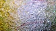 Reddish streaks cut across the surface of Tethys in this image. The streaks are narrow, curved lines on the moon’s surface, only a few miles wide but several hundred miles long. The yellowish tones on the left side of the view are a result of alteration of the moon’s surface by high-energy particles from Saturn’s magnetosphere. This particle radiation slams into the moon’s trailing hemisphere, modifying it chemically and changing its appearance in enhanced-color views like this one. The area of Tethys shown here is centered on 30 degrees north latitude, 187 degrees west longitude, and measures 305 by 258 miles (490 by 415 km) across. The original color images were obtained at a resolution of about 2,300 feet (700 m) per pixel on April 11, 2015. Image credit: NASA / JPL-Caltech / Space Science Institute.