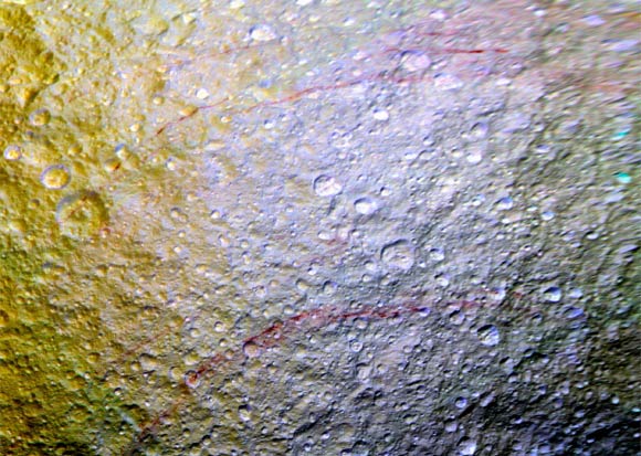 Reddish streaks cut across the surface of Tethys in this image. The streaks are narrow, curved lines on the moon’s surface, only a few miles wide but several hundred miles long. The yellowish tones on the left side of the view are a result of alteration of the moon’s surface by high-energy particles from Saturn’s magnetosphere. This particle radiation slams into the moon’s trailing hemisphere, modifying it chemically and changing its appearance in enhanced-color views like this one. The area of Tethys shown here is centered on 30 degrees north latitude, 187 degrees west longitude, and measures 305 by 258 miles (490 by 415 km) across. The original color images were obtained at a resolution of about 2,300 feet (700 m) per pixel on April 11, 2015. Image credit: NASA / JPL-Caltech / Space Science Institute.