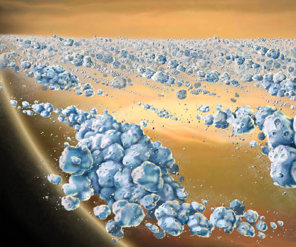 This is an artist concept of a close-up view of Saturn’s ring particles. The planet Saturn is seen in the background (yellow and brown). The particles (blue) are composed mostly of ice, but are not uniform. They clump together to form elongated, curved aggregates, continually forming and dispersing. The space between the clumps is mostly empty. The largest individual particles shown are a few meters across. Image credit: NASA.
