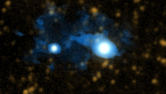 Using the Cosmic Web Imager (CWI) to study a system with two quasars 10 billion light-years away, the astronomers have unveiled a protogalaxy being fed cool gas by a filament of the cosmic web. The quasar UM 287 is the larger object at right; the newly-discovered protogalaxy is above and to the left of UM 287. This picture combines a visible light image of the system with CWI data; a filament of the cosmic web can be seen funneling cold gas onto the protogalaxy. Image credit: Chris Martin / PCWI / Caltech.