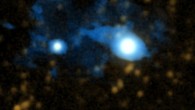 Using the Cosmic Web Imager (CWI) to study a system with two quasars 10 billion light-years away, the astronomers have unveiled a protogalaxy being fed cool gas by a filament of the cosmic web. The quasar UM 287 is the larger object at right; the newly-discovered protogalaxy is above and to the left of UM 287. This picture combines a visible light image of the system with CWI data; a filament of the cosmic web can be seen funneling cold gas onto the protogalaxy. Image credit: Chris Martin / PCWI / Caltech.