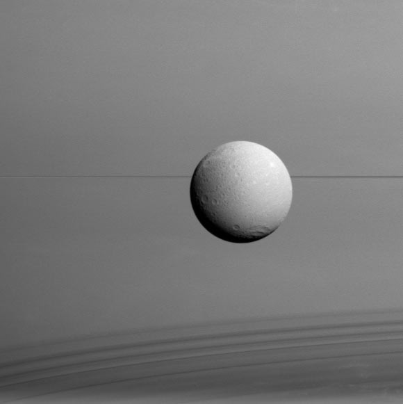 Dione hangs in front of Saturn and its icy rings in this view. The image was obtained in visible light with the wide-angle camera on Cassini on August 17. The view was acquired at a distance of approximately 45,000 miles (73,000 km) from Dione and at a Sun-Dione-spacecraft, or phase, angle of 35 degrees. North on Dione is up. Image credit: NASA / JPL-Caltech / Space Science Institute.