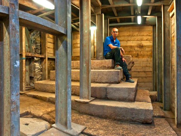 IAA archaeologist Dr Joe Uziel sitting atop the stepped structure. Image credit: Shai Halevy / Israel Antiquities Authority.