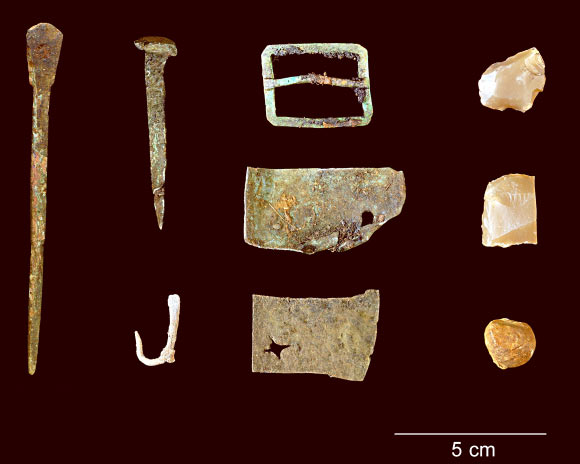 A representative collection of artifacts discovered in July 2015 includes, from left: part of a set of dividers, a nail, a fishhook, a buckle, sheet copper, gun flints and a musket ball. Image credit: Dave McMahan / Sitka Historical Society.
