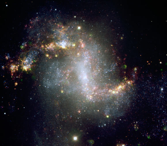 This image shows the spiral galaxy NGC 1313. The very active state of this galaxy is very evident from the image, showing many star formation regions. A great number of supershell nebulae, that is, cocoon of gas inflated and etched by successive bursts of star formation, are visible. The green nebulosities are regions emitting in the ionized oxygen lines and may harbour clusters with very hot stars. This composite image is based on images obtained with the FORS1 instrument on one of the 8.2-m Unit Telescope of ESO’s Very Large Telescope. Astronomers determined that this galaxy harbors a black hole 5,000 times more massive than our Sun. Image credit: ESO.