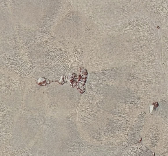 In this 75-mile (120-km) section, taken from the larger, high-resolution mosaic above, the textured surface of the plain surrounds two isolated ice mountains. Image credit: NASA / Johns Hopkins University Applied Physics Laboratory / Southwest Research Institute.