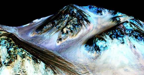 These dark, narrow, 100 meter-long recurring slope lineae flowing downhill on Mars are inferred to have been formed by contemporary flowing water. Recently, scientists detected hydrated salts on these slopes at Hale crater, corroborating their original hypothesis that the streaks are indeed formed by liquid water. The blue color seen upslope of the dark streaks are thought not to be related to their formation, but instead are from the presence of the mineral pyroxene. Image credit: NASA / JPL / University of Arizona.