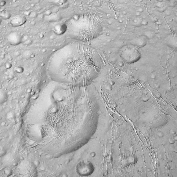 Cassini spied this tight trio of craters as it approached Enceladus for a close flyby on October 14, 2015. The craters, located at high northern latitudes, are sliced through by thin fractures - part of a network of similar cracks that wrap around the snow-white moon. The image was taken in visible light at a distance of 6,000 miles (10,000 km) from Enceladus. Image credit: NASA / JPL-Caltech / Space Science Institute.