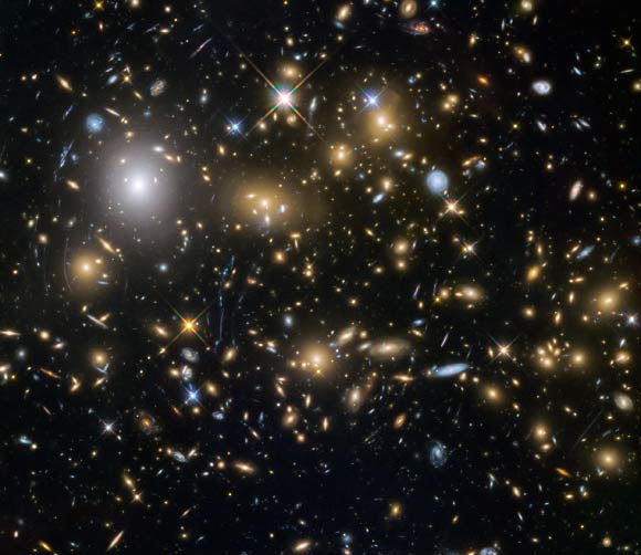 New images from the NASA/ESA Hubble Space Telescope show the faintest and earliest known galaxies in the Universe. This image shows the galaxy cluster MACSJ0717.5+3745 (MACS0717). It is one of the most massive galaxy clusters known, and it is also the largest known gravitational lens. Of all of the galaxy clusters known and measured, this cluster lenses the largest area of the sky. Image credit: NASA / ESA / HST Frontier Fields Team / STScI.