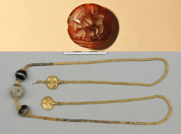 Top: this is one of more than four dozen seal stones with intricate Minoan designs found in the tomb. Long-horned bulls and, sometimes, human bull jumpers soaring over their horns are a common motif in Minoan designs. Bottom: this unique necklace measures more than 30-inches long and features two gold pendants decorated with ivy leaves. It was found near the neck of the warrior's skeleton. Image credit: University of Cincinnati.