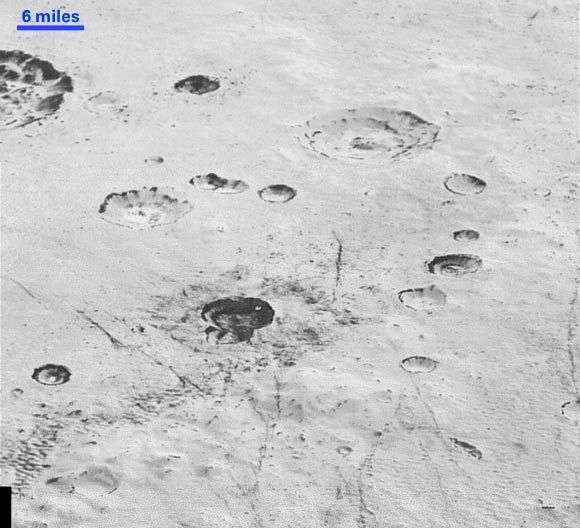 This image from New Horizons reveals new details of Pluto’s rugged, icy cratered plains. Notice the layering in the interior walls of many craters. The darker crater in the lower center is apparently younger than the others, because dark material ejected from within has not been erased and can still be made out. The origin of the many dark linear features trending roughly vertically in the bottom half of the image is under debate, but may be tectonic. Most of the craters seen here lie within the 155-mile (250-km)-wide Burney Basin, whose outer rim or ring forms the line of hills or low mountains at bottom. The basin is named after Venetia Burney, the English schoolgirl who first proposed the name Pluto for the newly discovered planet in 1930. The top of the image is to Pluto’s northwest. Image credit: NASA / Johns Hopkins University Applied Physics Laboratory / Southwest Research Institute.