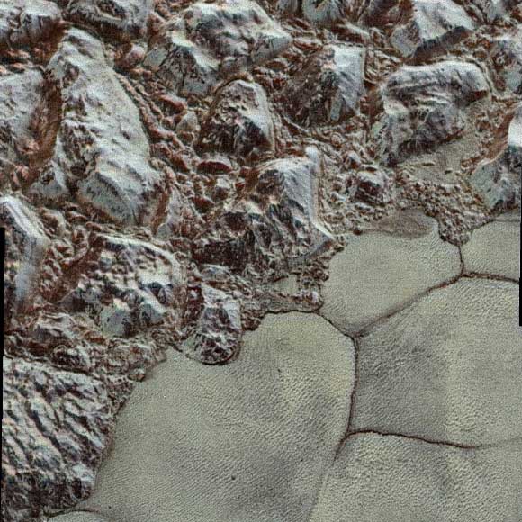 Mountainous shoreline of Sputnik Planum: in this enhanced color image, great blocks of Pluto’s water-ice crust appear jammed together in al-Idrisi mountains. Some mountain sides appear coated in dark material, while other sides are bright. Several sheer faces appear to show crustal layering, perhaps related to the layers seen in some of Pluto’s crater walls. The mountains end abruptly at the shoreline of Sputnik Planum, where exotic ices of the plain form a nearly level surface, broken only by the fine trace work of striking, cellular boundaries and the textured surface of the plain’s ices. Image credit: NASA / Johns Hopkins University Applied Physics Laboratory / Southwest Research Institute.