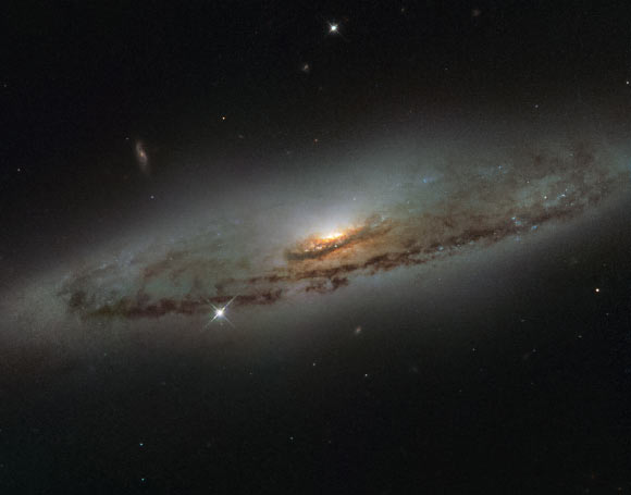 This image from Hubble’s WFPC2 camera shows the spiral galaxy NGC 4845. The galaxy’s orientation clearly reveals the galaxy’s striking spiral structure: a flat and dust-mottled disc surrounding a bright galactic bulge. Image credit: NASA / ESA / Hubble / S. Smartt, Queen's University Belfast.