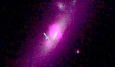 This composite image from the NASA/ESA Hubble Space Telescope and NASA’s Chandra X-ray Observatory shows the galaxy SDSS J112659.54+294442.8. The arrow points to the black hole that lost most of its stars due to gravitational stripping processes. Image credit: NASA / ESA / Hubble Team / Chandra Team / Julia M. Comerford et al.