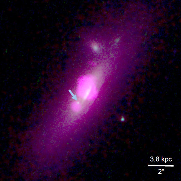This composite image from the NASA/ESA Hubble Space Telescope and NASA’s Chandra X-ray Observatory shows the galaxy SDSS J112659.54+294442.8.  The arrow points to the black hole that lost most of its stars due to gravitational stripping processes. Image credit: NASA / ESA / Hubble Team / Chandra Team / Julia M. Comerford et al.