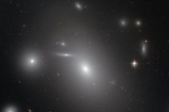 This image shows NGC 4889 (largest object) in front of hundreds of background galaxies. Image credit: NASA / ESA.