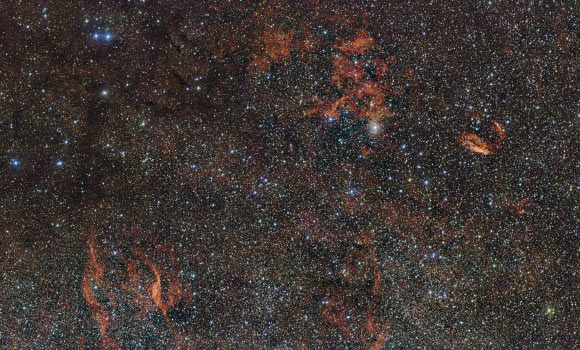 In this wide-field image from ESO’s VLT Survey Telescope wisps of gas are illuminated by massive stars that have only recently ignited and are still buried deep in thick dust clouds. Image credit: ESO.