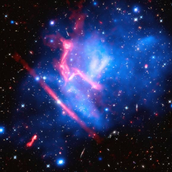 This composite image of the galaxy cluster MACS J0717 was made by combining data from NASA’s Chandra and Hubble space telescopes, and NRAO’s Jansky Very Large Array. Image credit: NASA / ESA / CXC / NRAO / AUI / NSF / STScI / R. van Weeren, Harvard-Smithsonian Center for Astrophysics / J. Lotz, STScI / HFF Team.
