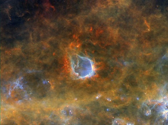 The emission nebula RCW 120 seen by Herschel. It lies about 4,300 light-years away. A star at the center, not visible at these infrared wavelengths, has blown a beautiful bubble around itself with the mighty pressure of the light it radiates. The pressure is so strong that it has compressed the material at the edge of the bubble, causing it to collapse and triggering the birth of new stars. Image credit: ESA / Herschel / PACS / SPIRE / Hi-GAL Project / G. Li Causi, IAPS / INAF.