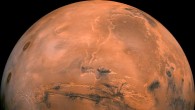 Mosaic of the Valles Marineris hemisphere of Mars projected into point perspective, a view similar to that which one would see from a spacecraft. The distance is 1,550 miles (2,500 km) from the surface of the planet. The mosaic is composed of 102 Viking Orbiter images of Mars. The center of the scene shows the entire Valles Marineris canyon system, over 1,240 miles (2,000 km) long and up to 5 miles (8 km) deep, extending form Noctis Labyrinthus, the arcuate system of graben to the west, to the chaotic terrain to the east. Many huge ancient river channels begin from the chaotic terrain from north-central canyons and run north. The three Tharsis volcanoes (dark red spots), each about 15.5 miles (25 km) high, are visible to the west. South of Valles Marineris is very ancient terrain covered by many impact craters. Image credit: NASA / JPL-Caltech.