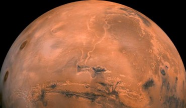 Mosaic of the Valles Marineris hemisphere of Mars projected into point perspective, a view similar to that which one would see from a spacecraft. The distance is 1,550 miles (2,500 km) from the surface of the planet. The mosaic is composed of 102 Viking Orbiter images of Mars. The center of the scene shows the entire Valles Marineris canyon system, over 1,240 miles (2,000 km) long and up to 5 miles (8 km) deep, extending form Noctis Labyrinthus, the arcuate system of graben to the west, to the chaotic terrain to the east. Many huge ancient river channels begin from the chaotic terrain from north-central canyons and run north. The three Tharsis volcanoes (dark red spots), each about 15.5 miles (25 km) high, are visible to the west. South of Valles Marineris is very ancient terrain covered by many impact craters. Image credit: NASA / JPL-Caltech.