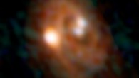 Combined ALMA and VLA image of the L1448 IRS3B system, with two young stars at the center and a third distant from them; spiral structure in the dusty disk surrounding them indicates instability in the disk. Image credit: Bill Saxton / ALMA / ESO / NAOJ / NRAO / AUI / NSF.