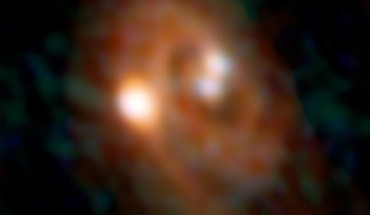 Combined ALMA and VLA image of the L1448 IRS3B system, with two young stars at the center and a third distant from them; spiral structure in the dusty disk surrounding them indicates instability in the disk. Image credit: Bill Saxton / ALMA / ESO / NAOJ / NRAO / AUI / NSF.