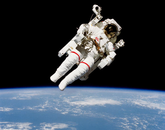 Astronaut Bruce McCandless II, STS 41-B mission specialist, participates in a historical spacewalk. He is pictured a few meters away from the cabin of the Earth-orbiting Space Shuttle Challenger. This spacewalk represented the first use of a nitrogen-propelled, hand-controlled device called the Manned Maneuvering Unit (MMU), which allows for much greater mobility than that afforded previous space walkers who had to use restrictive tethers. Image credit: NASA.
