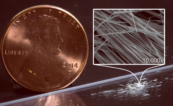 Fuzzy white clusters of nanowires on a lab bench, with a penny for scale. Assembled with the help of diamondoids, the nanowires can be seen with the naked eye because the strong mutual attraction between their diamondoid shells makes them clump together, in this case by the millions. At top right, an image made with a scanning electron microscope shows nanowire clusters magnified 10,000 times. Image credit: SLAC National Accelerator Laboratory / Hao Yan / SIMES.
